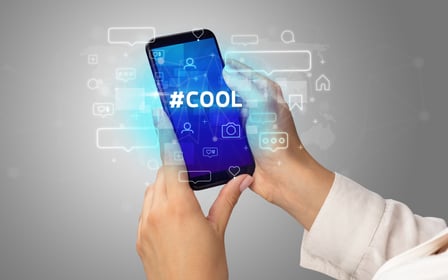 Female hand typing on smartphone with #COOL inscription, social media concept