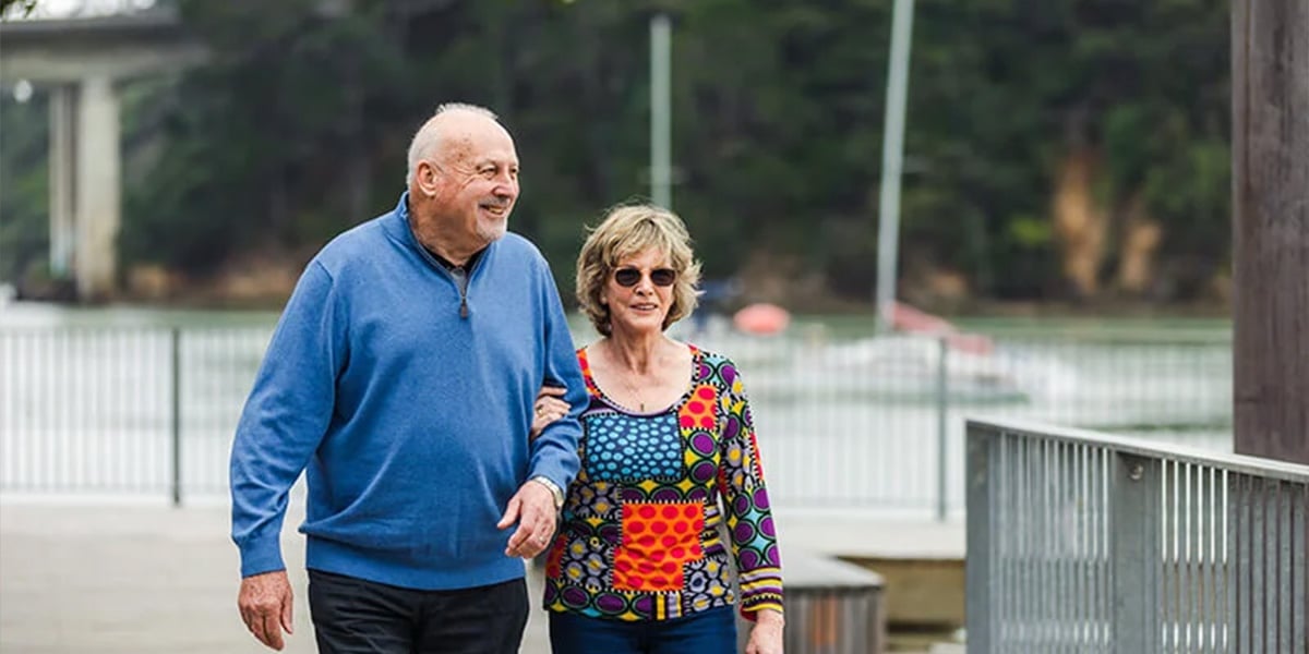 A retired couple enjoy a walk along the bay