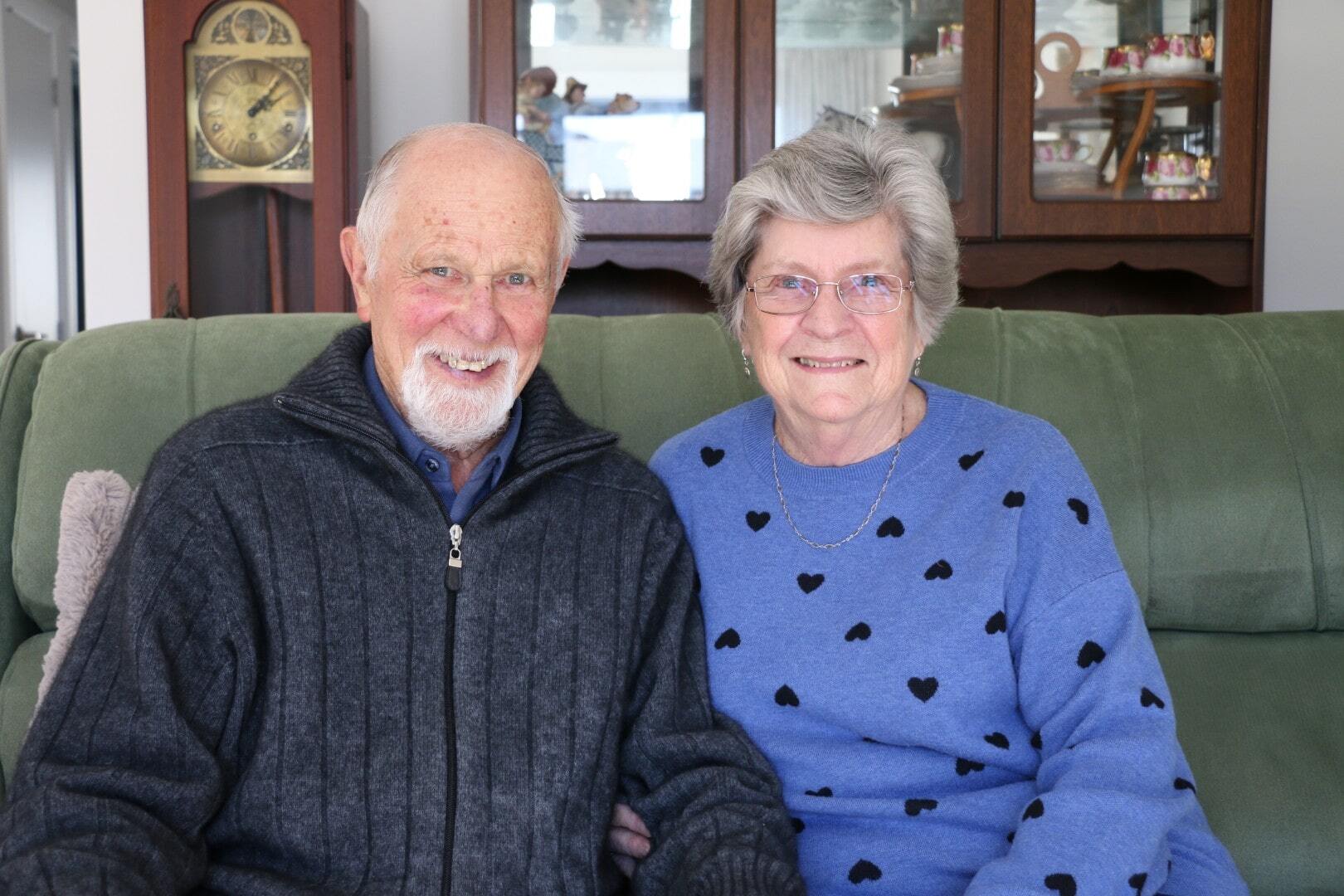 Smiling older couple sit together in homely surroundings