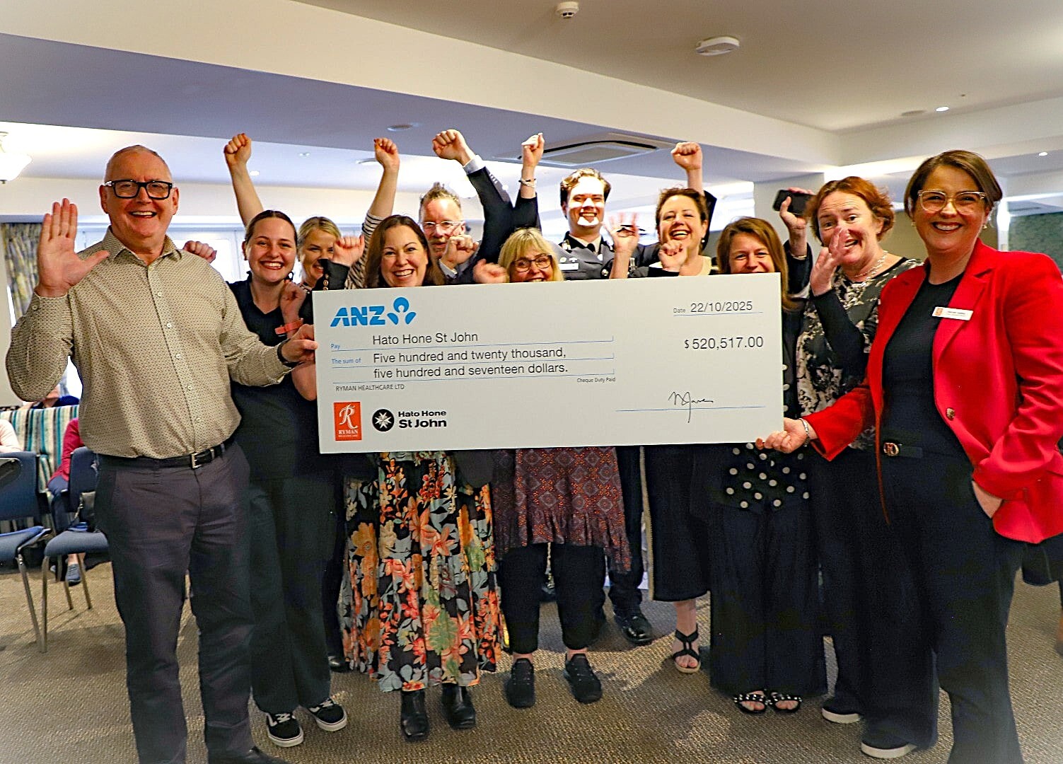 A very happy group of people celebrate while holding a giant cheque 