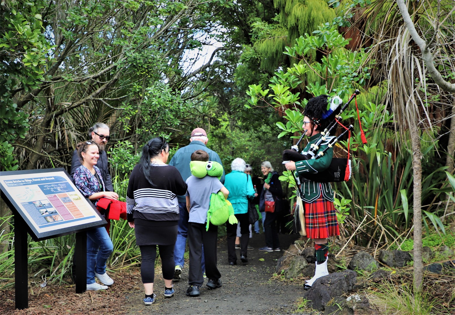 People walking and man playing bagpipes