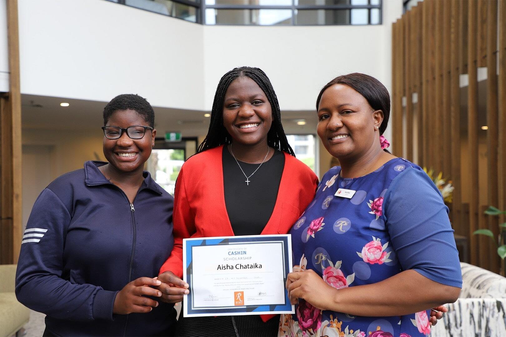 A mother wearing a caregiver uniform celebrates an award with her two daughters